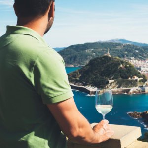 man on balcony with wine looking at view